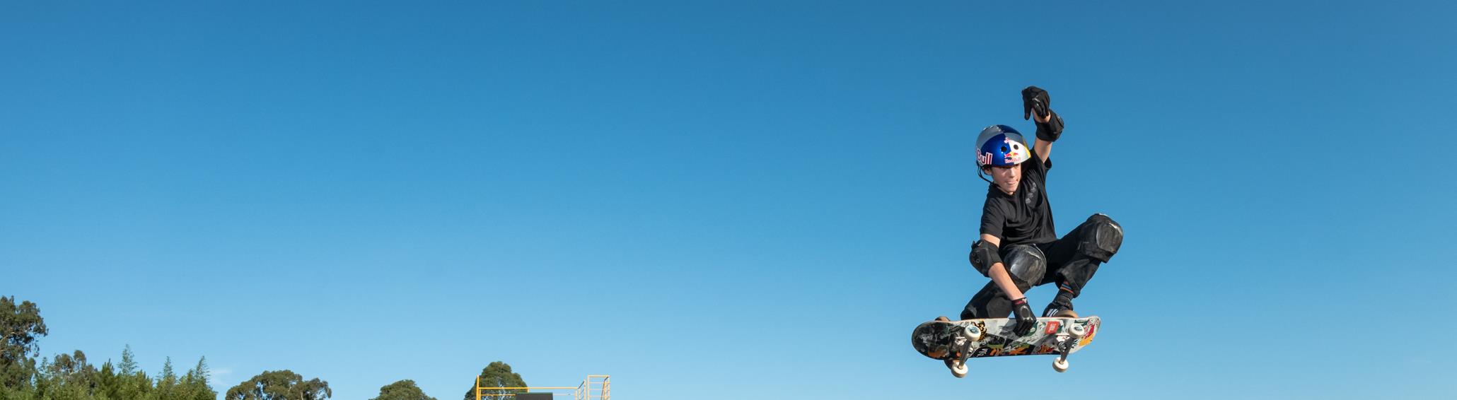 Skatista no ar contra céu azul
